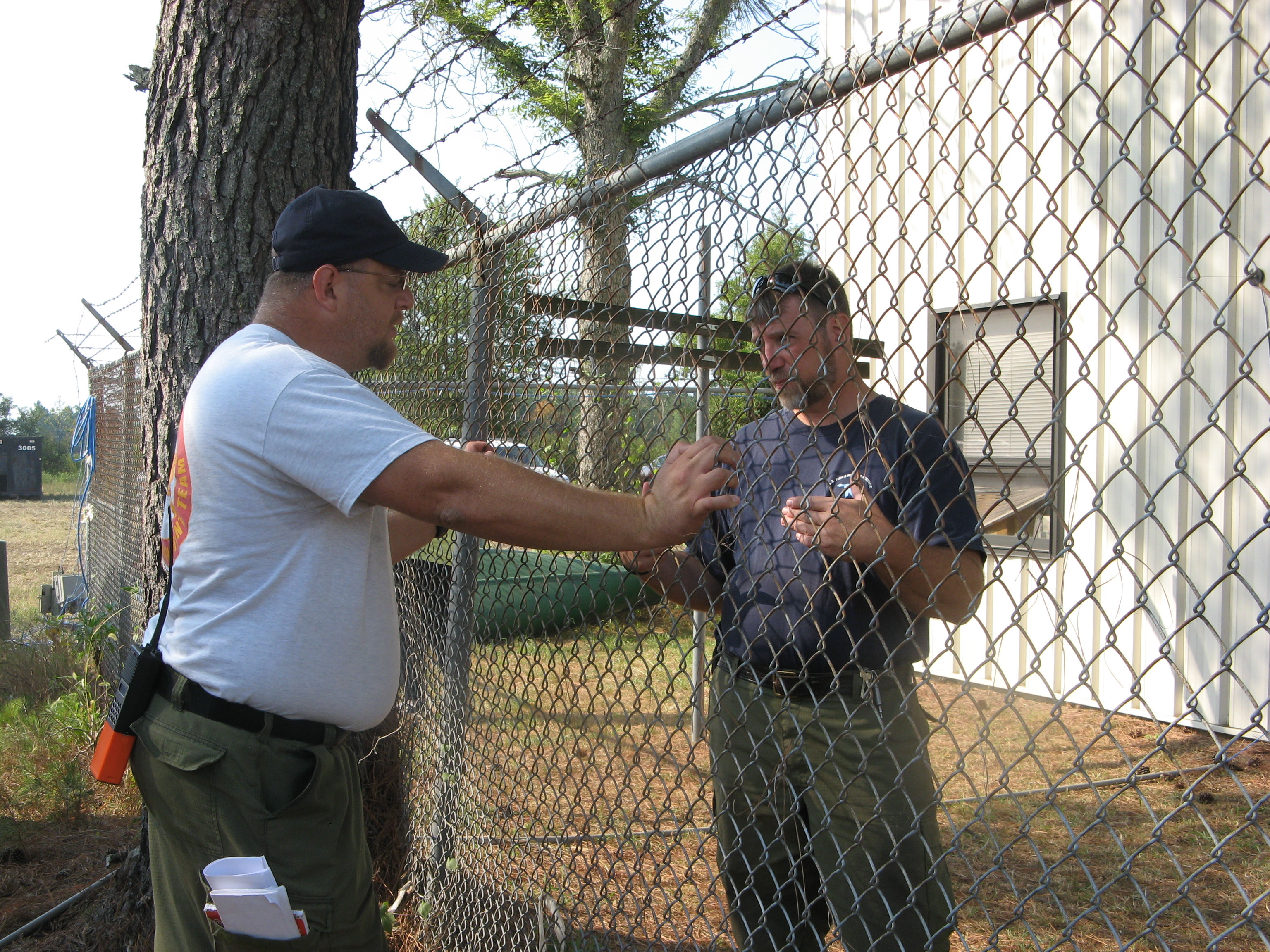 two men divided by a barbed wire fence